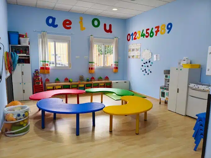 Aula infantil en CEI Caracola, con mesas de colores y zona de juegos simbólicos.