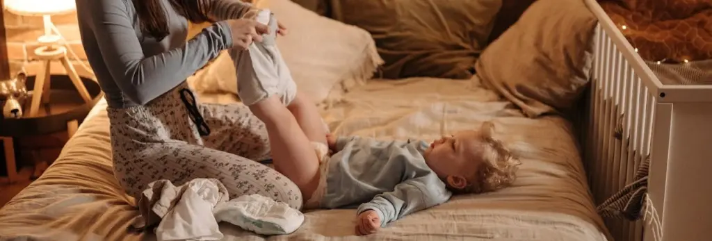 Madre ayudando a un niño pequeño durante el cambio de pañal